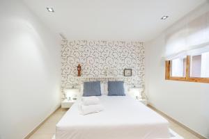 een witte slaapkamer met een groot bed met blauwe kussens bij Gatova Sunset Retreat in Gátova +39 foto's