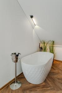 a white bath tub sitting on a wooden floor next to a lamp at Chamber Luxury House in Kaunas