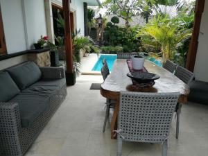 Una mesa y sillas en un patio con piscina. en Pondok Pradhipta, en Dalung