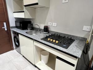 a small kitchen with a stove and a sink at Balcony studio in Sheikh Zayed