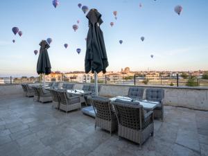 a patio with tables and umbrellas and hot air balloons at Cappadocia ByHan Hotel - Special Class in Uçhisar