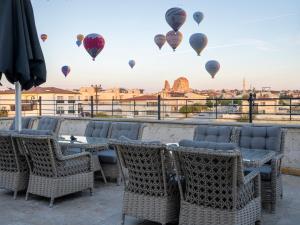 d'une terrasse avec des tables, des chaises et des montgolfières. dans l'établissement Cappadocia ByHan Hotel - Special Class, à Uçhisar