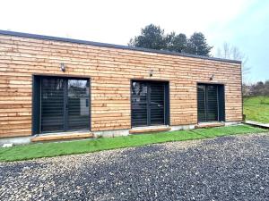 un bâtiment avec deux fenêtres et de l'herbe verte dans l'établissement Refuge des voyageurs Studio neuf - Horizon indépendant rez de jardin, à Plouédern