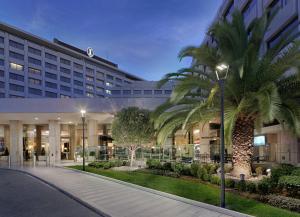 a hotel with palm trees in front of a building at Athenaeum Intercontinental by IHG in Athens
