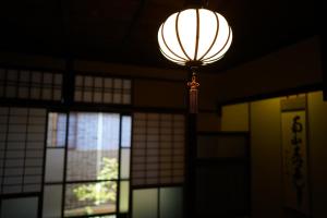 a lantern hanging from the ceiling in a building with windows at Ryokan Tori in Kyoto