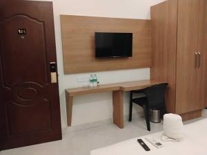 a hotel room with a desk with a tv on the wall at Hotel O Mirage Suites in Bengaluru