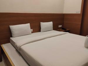 a bedroom with a large bed with white sheets and pillows at Hotel O Mirage Suites in Bengaluru