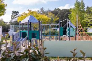 a playground behind a fence at Camping 4 étoiles - Piscine - cbgcb0b in Saint-Jean-de-Monts