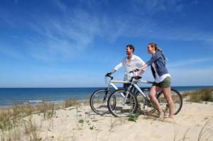 a man and a woman riding a bike on the beach at Camping 4 étoiles - Piscine - cbgcaig in Notre-Dame-de-Monts