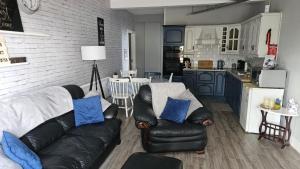 Il comprend un salon avec un canapé en cuir noir et une cuisine. dans l'établissement Farm Lodge, à Monaghan