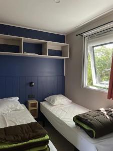 2 camas en una habitación con ventana y paredes azules en Camping 4 étoiles - Piscine - ccb0bif, en Apremont