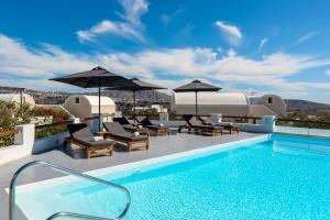 a pool on the roof of a house with umbrellas at Acrothea Suites and Villas - Akrotiri Caldera - Santorini in Akrotiri +102 photos