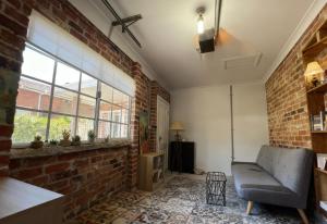 Burwood Family Guest Home في سيدني: غرفة معيشة مع جدار من الطوب وأريكة