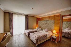 ein Hotelzimmer mit zwei Betten und einem Fenster in der Unterkunft grand Şeker hotel in Side