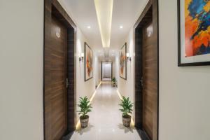 un couloir orné de peintures sur les murs et de plantes en pot dans l'établissement FabHotel Bless Inn, à Allahābād
