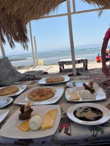 - une table avec des assiettes de nourriture sur la plage dans l'établissement Sea View Camp Nuweiba, à Wāsiţ