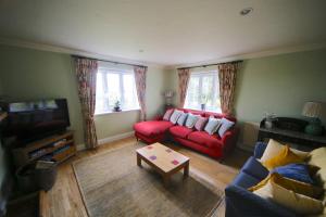 a living room with a red couch and a tv at 3-bedroom cottage set in a large enclosed garden in Thatcham
