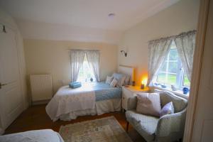 a bedroom with a bed and a couch and two windows at 3-bedroom cottage set in a large enclosed garden in Thatcham