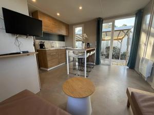 a kitchen and living room with a table and a refrigerator at Camping 4 étoiles - Piscine - ccbbecd in Le Grau-dʼAgde