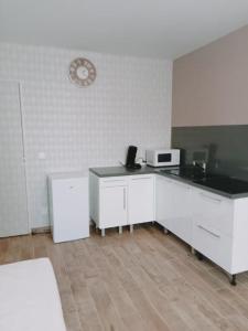 eine Küche mit weißen Schränken und einer Uhr an der Wand in der Unterkunft Studio de la ferme des huis 