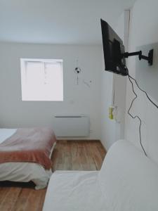 ein Schlafzimmer mit einem Bett und einem Fernseher an der Wand in der Unterkunft Studio de la ferme des huis 