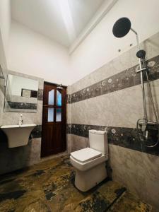 um banheiro com vaso sanitário, pia e chuveiro em Hotel UK Pasikuda em Kalkudah mais 13 fotografias