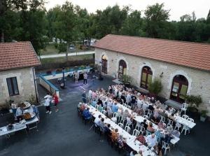 un groupe de personnes assises à des tables devant un bâtiment dans l'établissement Camping 3 étoiles - Piscine - ccbb0if, à Montpon-Ménestérol 189 autres photos