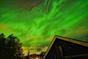 an aurora in the sky over a cabin at Riverfront Aurora Chalet in Kiruna
