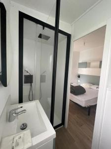 a bathroom with a sink and a bedroom with a bed at ZEcamping 4 étoiles animaux acceptés bain à remous sauna et solarium in Apremont