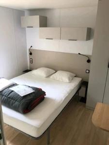 a white bed with two pillows on it with at ZEcamping 4 étoiles animaux acceptés bain à remous sauna et solarium in Apremont