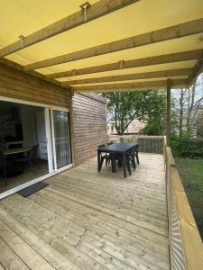a wooden deck with a picnic table under awning at ZEcamping 4 étoiles animaux acceptés bain à remous sauna et solarium in Apremont +103 photos