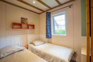 zwei Betten in einem Zimmer mit Fenster in der Unterkunft Camping 4 étoiles - Piscine - cbgcb0b in Saint-Jean-de-Monts