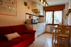 un soggiorno con un divano rosso e una cucina di Casa vacanze Danoi Dolomiti a Canale dʼAgordo