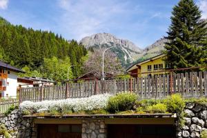 una recinzione di fronte a una casa con montagne sullo sfondo di Casa vacanze Danoi Dolomiti a Canale dʼAgordo