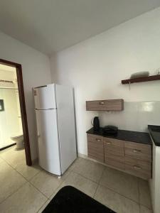 a kitchen with a white refrigerator and wooden cabinets at Renascer Suites in Búzios