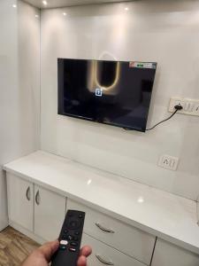 大诺伊达StayAtGhar-Near Expo Mart的电视机前有遥控器的人