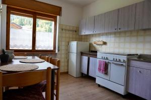 una cucina con un tavolo e un frigorifero bianco di Casa vacanze Danoi Dolomiti a Canale dʼAgordo Altre 23 foto