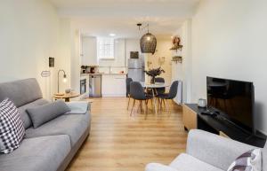 a living room with a gray couch and a kitchen at Apartamento Vico in Escarrilla