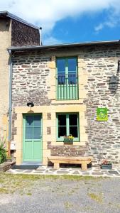 un bâtiment en pierre avec une porte verte et un banc dans l'établissement Gite de la semoy, à Haulmé