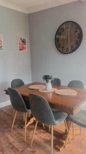une table à manger avec des chaises et une horloge murale dans l'établissement Wattle Cottage, à Cootamundra