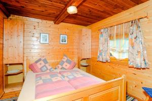 Un dormitorio con una cama en una cabaña de troncos en Almhütte Haritzer, en Schachnern