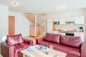 Una sala de estar con dos sofás rojos y una cocina. en Residenz Meeresblick A Fewo 5, en Rerik