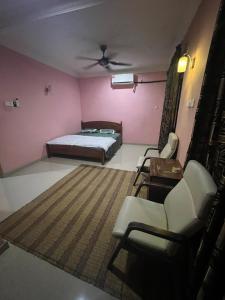 a bedroom with pink walls and a bed and chairs at D'Huda Homestay in Sungai Petani