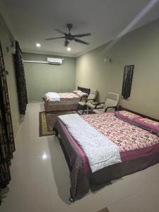 a bedroom with two beds and a ceiling fan at D'Huda Homestay in Sungai Petani