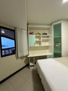 ein Schlafzimmer mit Bett, Schreibtisch und Fenster in der Unterkunft Apartamento familiar com vista para o mar em Guarapari Praia do Morro, frente ao Marlim!!! in Guarapari