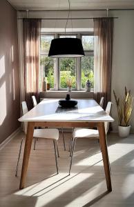 une salle à manger avec une table et des chaises blanches dans l'établissement Modern vacation Home - Close to sea and nature., à Hejls
