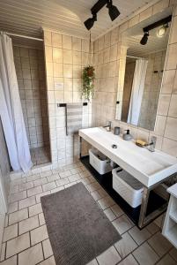 une salle de bains avec un lavabo blanc et un miroir dans l'établissement Modern vacation Home - Close to sea and nature., à Hejls