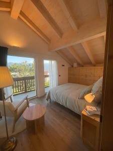 Un dormitorio con una cama, una silla y una ventana en Appartamento La Téza, en Lavarone