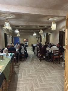 un groupe de personnes assises à des tables dans un restaurant dans l'établissement Hôtel Camping La Liberté, à Merzouga