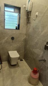 une salle de bain avec des toilettes blanches et une fenêtre dans l'établissement The Royal Ascot Holiday Home with private pool, à Alibaug
